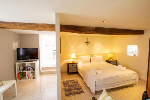 une chambre avec un lit blanc et une télévision dans l'établissement Le tilleul, à Saint-Sauveur