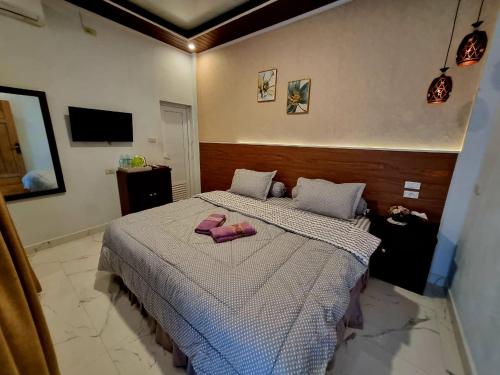 a bedroom with a bed with pink slippers on it at Alya Homestay Meulaboh in Meulaboh