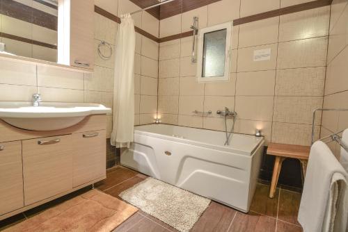 a bathroom with a bath tub and a sink at Green Village in Xylokastro