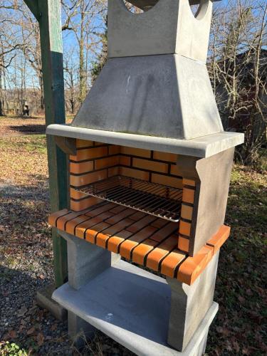 un four en briques assis au-dessus d'un grill dans l'établissement Chalet d'ARTAGNAN à la ferme, à Pouylebon