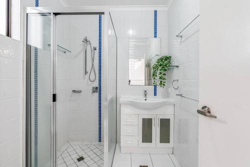 a white bathroom with a shower and a sink at Casa Del Mar - Poolside Retreat Near Trinity Beach in Trinity Beach