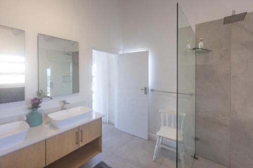 a bathroom with two sinks and a glass shower at Simply Stunning but smaller in Cape St Francis