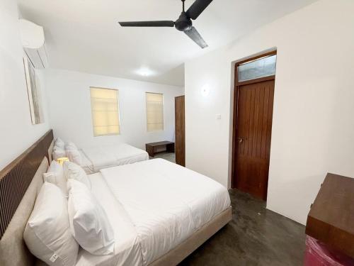 a bedroom with two beds and a ceiling fan at Villa Margot by Ceylon Spaces in Pamunugama