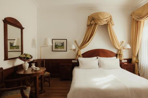 ein Schlafzimmer mit einem Bett, einem Tisch und einem Spiegel in der Unterkunft Corso am Graben in Bruneck