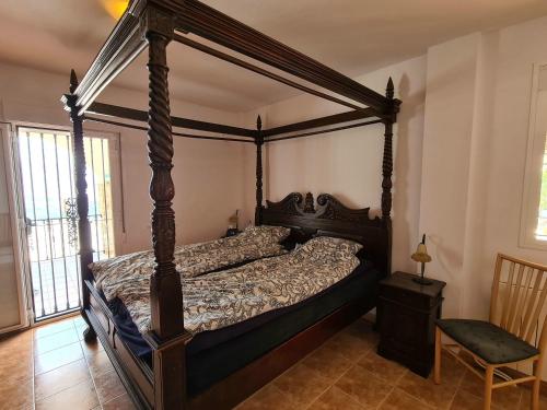 a bedroom with a canopy bed and a chair at Casa La Vista in Canillas de Albaida