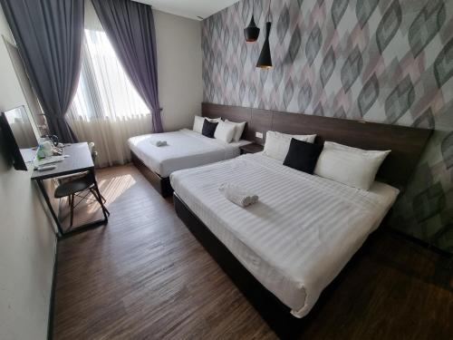 a hotel room with two beds and a desk at The Square Hotel in Skudai