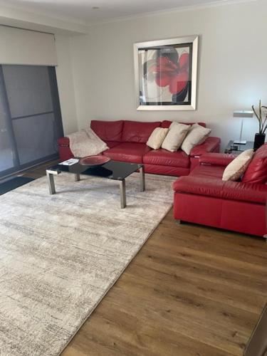 a living room with a red couch and a table at Bannister Street Apartments in Fremantle