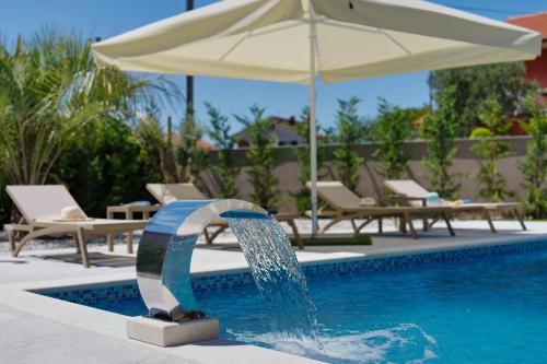 a fountain in a pool with an umbrella at Pieron & Bavigo Villas - Spa Oasis in Marčana