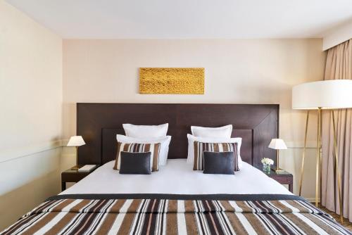 a bedroom with a large white bed with two pillows at Hôtel Barrière Le Gray d'Albion in Cannes