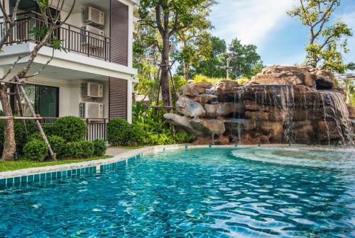 a swimming pool with a waterfall in front of a building at The Title KR Beach Condotel Rawai Beach in Rawai Beach