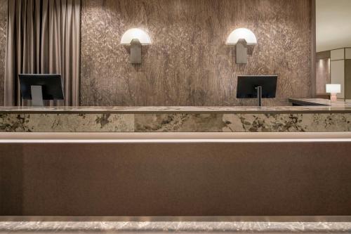 a reception desk in a hotel lobby with mirrors at AC Hotel Milano by Marriott in Milan