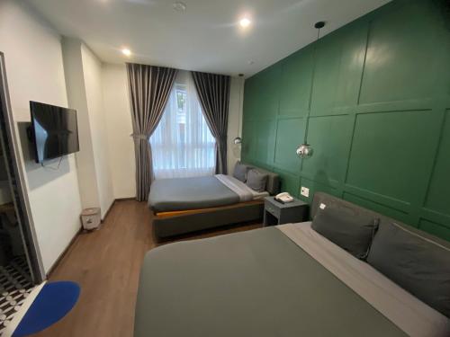 ein kleines Zimmer mit einem Bett und einer grünen Wand in der Unterkunft Hoang Gia Hotel in Da Lat