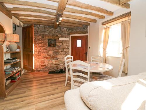 a living room with a table and a brick wall at Holme Fell View in Sedbergh