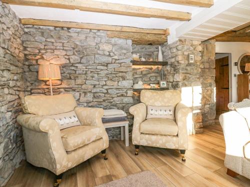 a bedroom with two chairs and a stone wall at Holme Fell View in Sedbergh