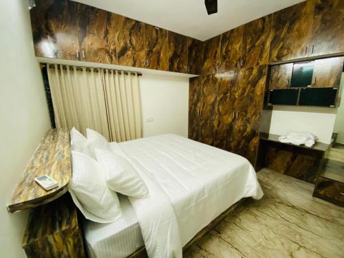 a bedroom with a white bed and a wooden wall at Echoes in Nandigunda