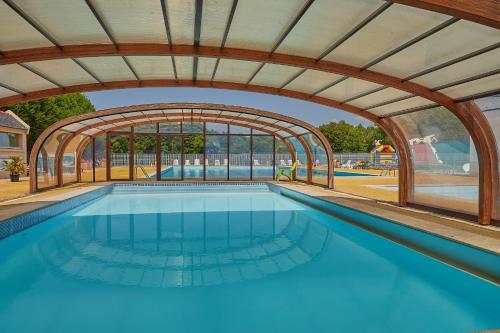une piscine intérieure avec une arche et une piscine dans l'établissement Camping Le Bois de Pleuven, à Saint-Yvy