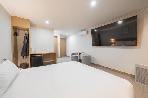 a bedroom with a white bed and a television at Cheonan H-Avenue Cheonan Buldang in Cheonan