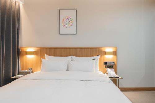 a bedroom with a white bed and a phone at Cheonan H-Avenue Cheonan Buldang in Cheonan