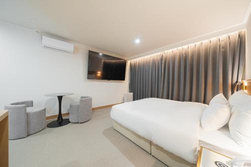 a bedroom with a white bed and a desk at Cheonan H-Avenue Cheonan Buldang in Cheonan