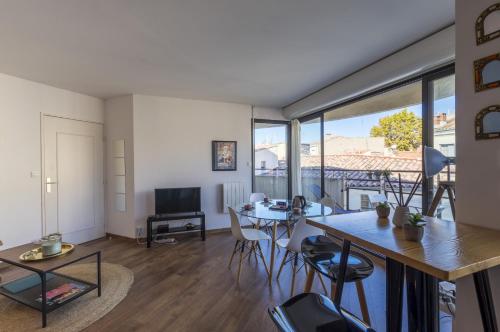 - un salon avec une table, des chaises et une grande fenêtre dans l'établissement Terrasse en ville - Premiere conciergerie, à Montpellier