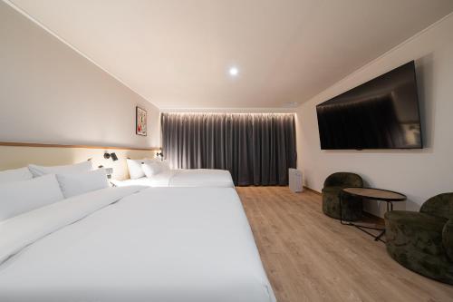a hotel room with two beds and a flat screen tv at Cheonan H-Avenue Cheonan Buldang in Cheonan