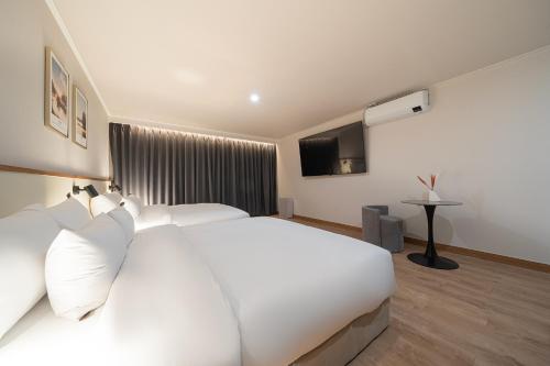 a bedroom with a large white bed and a television at Cheonan H-Avenue Cheonan Buldang in Cheonan