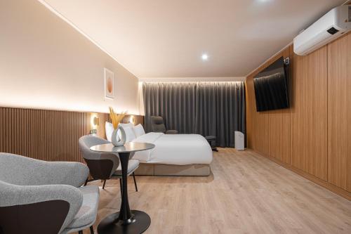a hotel room with a bed and a table and chairs at Cheonan H-Avenue Cheonan Buldang in Cheonan