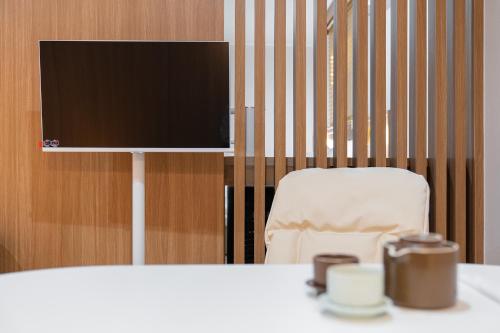 a table with a chair and a television on a wall at Cheonan H-Avenue Cheonan Buldang in Cheonan