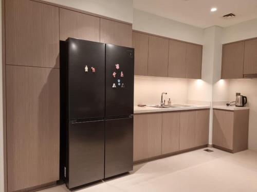 a kitchen with a black refrigerator and a sink at Luxury 2 Bedroom Act 1 Apartment in Dubai