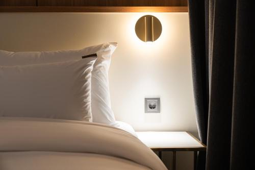 a bed with a white pillow and a light on the wall at Cheonan H-Avenue Cheonan Buldang in Cheonan