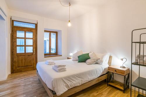 a bedroom with a bed with white sheets and a wooden floor at Casa Bar - Cozy Apartments Lake Como in Dongo