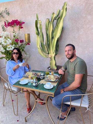 um homem e uma mulher sentados à mesa com comida em Riad Darchica em Marraquexe