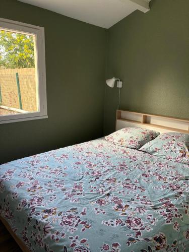 - une chambre avec un lit doté d'un couvre-lit floral et d'une fenêtre dans l'établissement St Cyprien Belle maison renovee avec jardin 4 a 6 p, à Saint-Cyprien