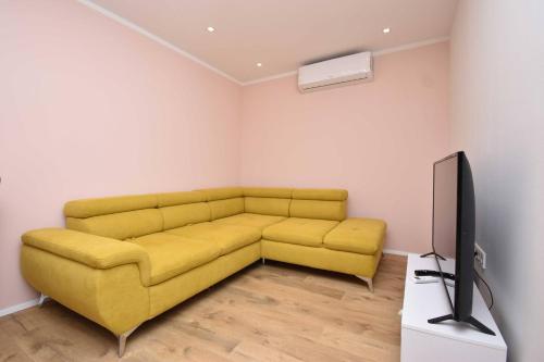 sala de estar con sofá amarillo y TV en Villa Blue Chill, en Brodarica