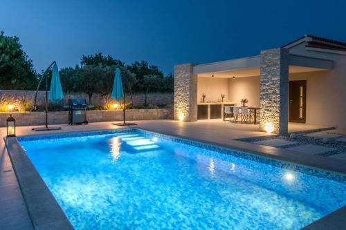 a swimming pool in front of a house at night at Villa Silentio in Marčana