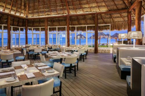 a restaurant with tables and chairs and the ocean at The Westin Resort & Spa Cancun in Cancún