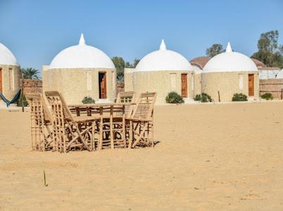 a table and chairs in the sand in front of a building at Gazrashek Siwa Hot spring& trips Haven in Siwa