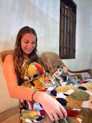a woman sitting in a chair holding two cats at Alass Ga For Pets Lovers in Trincomalee