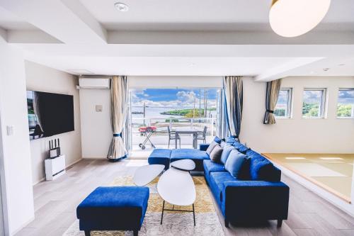 a living room with a blue couch and a tv at Coral Sea Villa OKINAWA MIYAKOJIMA in Miyako-jima