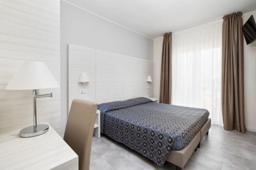 a bedroom with a bed and a table and a lamp at Hotel Marco Polo in Caorle