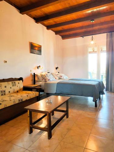 a bedroom with a bed and a table and a couch at Kapases Studios & Apartments in Peroulades