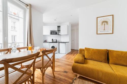 un salon avec une table et un canapé jaune dans l'établissement Appartement service 2 Pieces au Coeur du 19e - 4P, à Paris