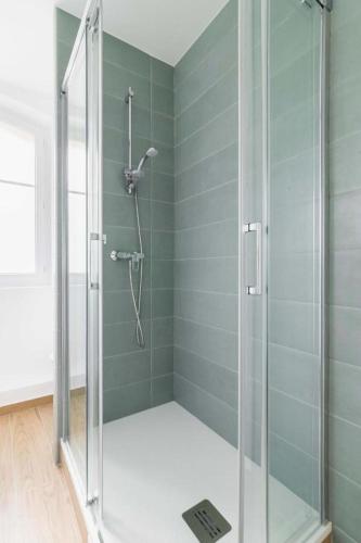 une douche avec une porte vitrée dans une salle de bain dans l'établissement Appartement service 2 Pieces au Coeur du 19e - 4P, à Paris