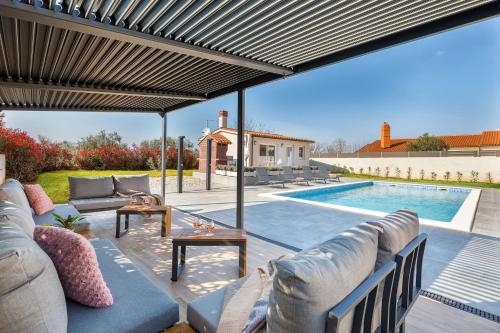 eine Terrasse mit einem Sofa und einem Pool in der Unterkunft Villa Berg II in Valbandon