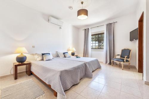 a white bedroom with a large bed and a chair at Loendros, Calma Moradia com Piscina Privada, Guia in Guia