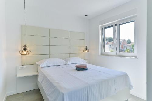 een witte slaapkamer met een groot wit bed en een raam bij Villa DIV with pool in Bibinje