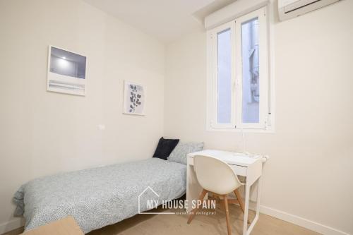 sypialnia z łóżkiem, stołem i oknem w obiekcie MyHouseSpain - Acogedor piso con patio en Chamberi w Madrycie