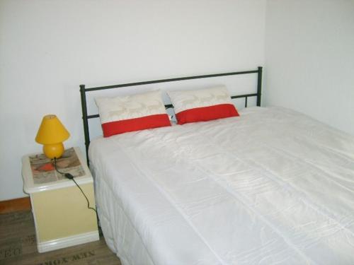 - un lit avec des oreillers rouges et blancs et une lampe dans l'établissement Gîte dans un village médiéval, à Auzon