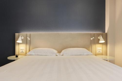 a large bed with two white pillows and two tables at Adesso Hotel in Rome
