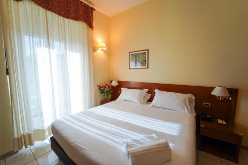 a bedroom with a large white bed and a window at Hotel Adria in Bari